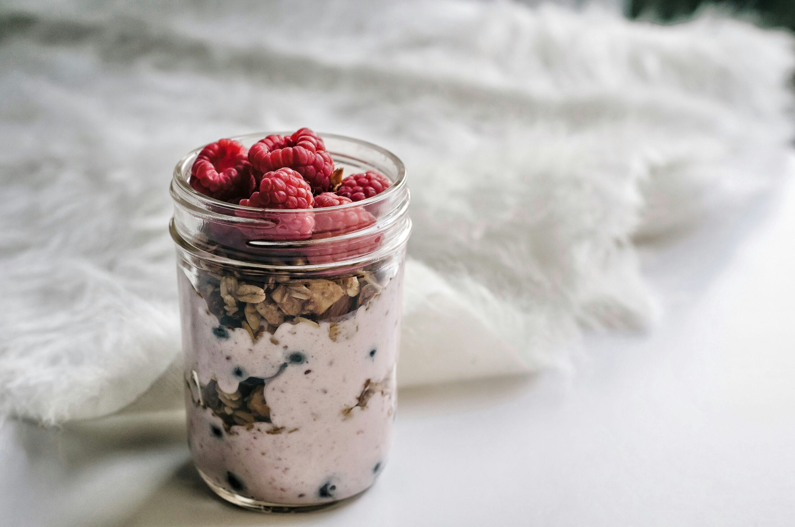 A glass jar filled with creamy overnight oats topped with fruit, representing a simple, healthy breakfast option.