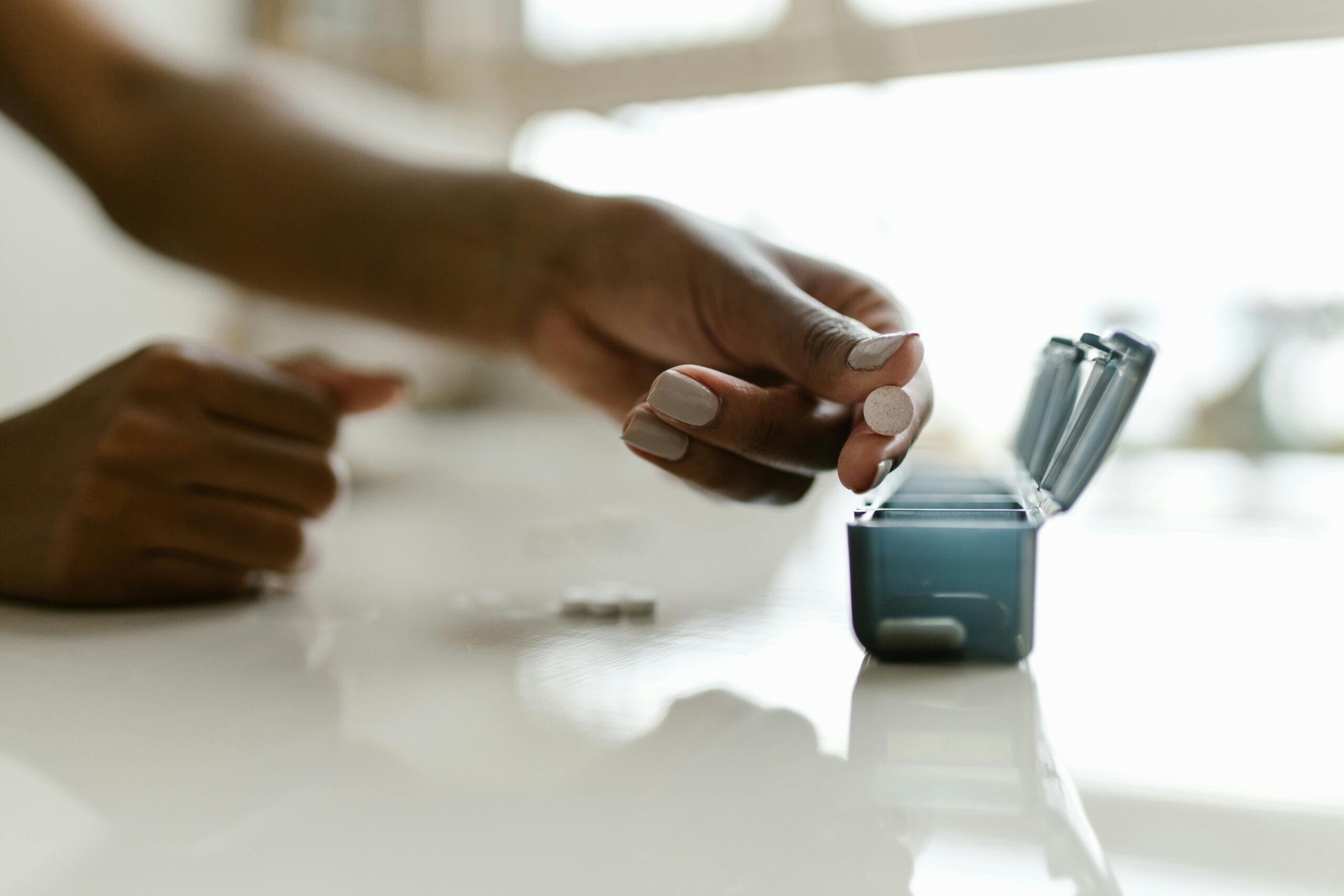 Man organizing daily supplements in a pill box for a fitness routine