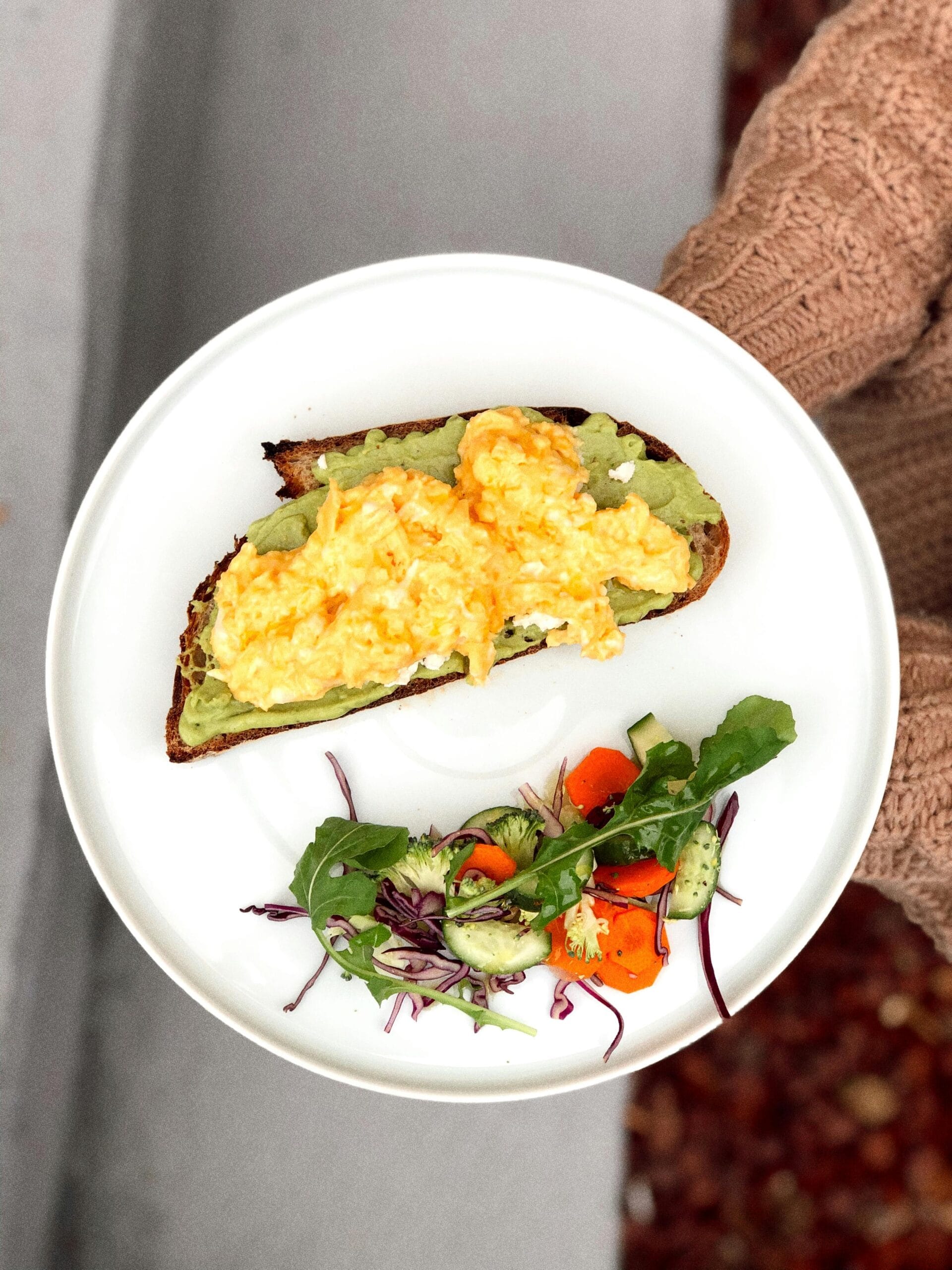 Plate with scrambled eggs and avocado toast for a balanced healthy breakfast meal.
