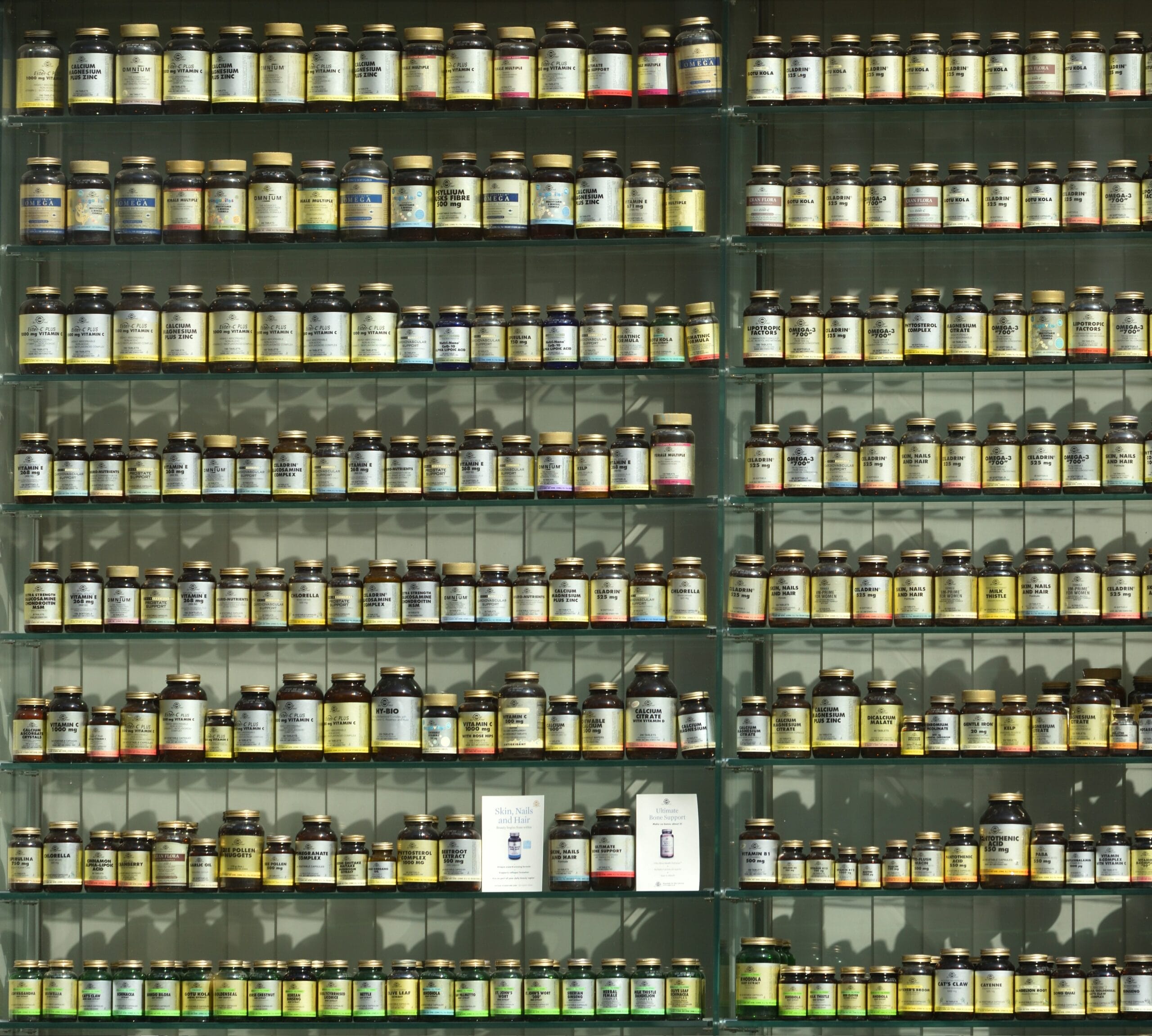 Pharmacy shelves filled with different supplement bottles showing how too many supplements can overwhelm consumers