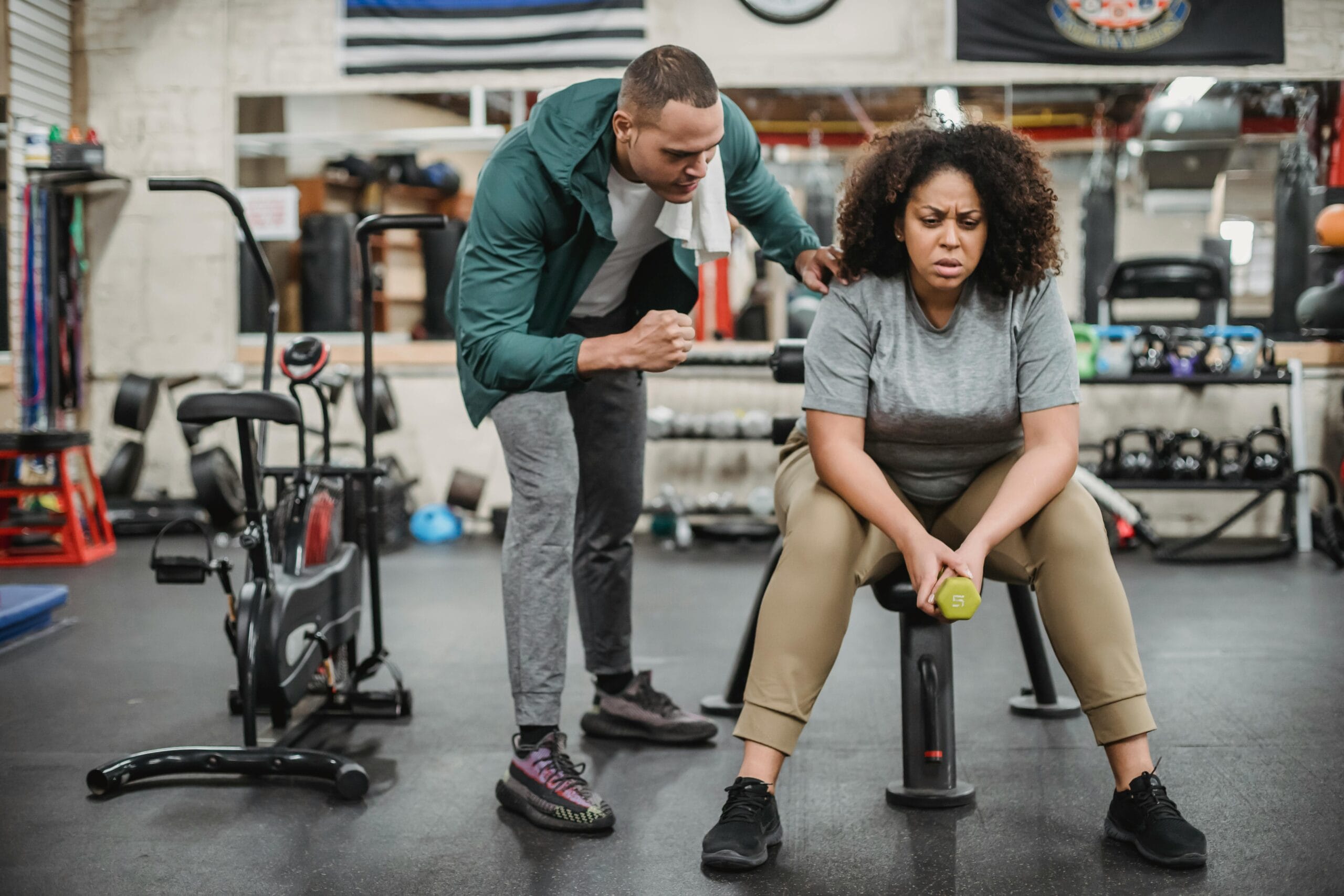 woman resting after a workout while a trainer offers motivation during a difficult fitness session