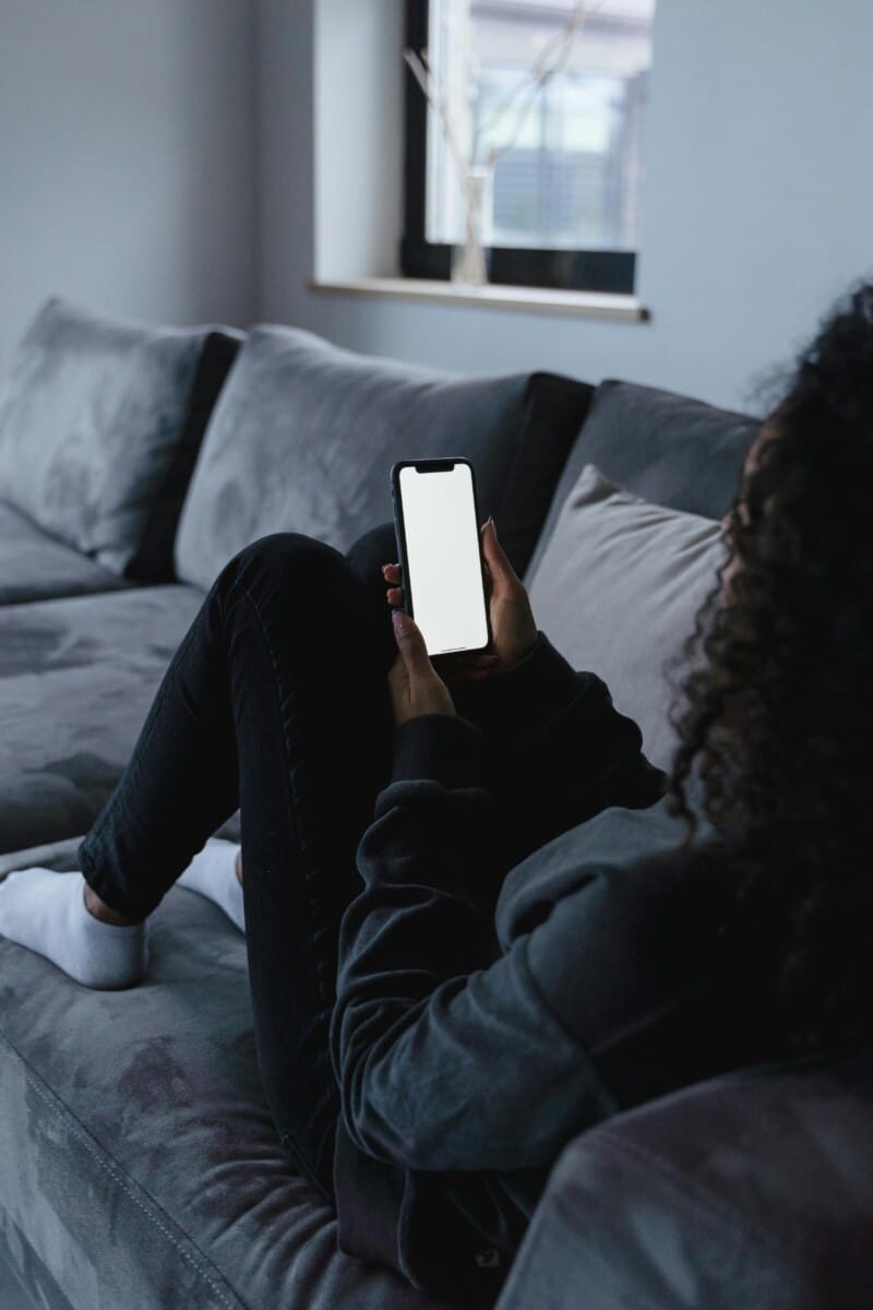 woman scrolling on phone while lying on couch